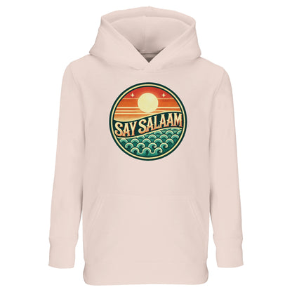 Say Salaam Sunset Glow Part-Recycled Cotton-Poly Kids Hoodie in creamy pink, a soft blush shade similar to oyster pink with gentle pastel warmth. The bold circular sunset logo contrasts beautifully against the light base, featuring layered sun and wave detailing in retro tones. Made from a cotton and recycled polyester blend with brushed fleece lining for comfort. Relaxed fit hoodie ideal for school, community events and modest streetwear styling.