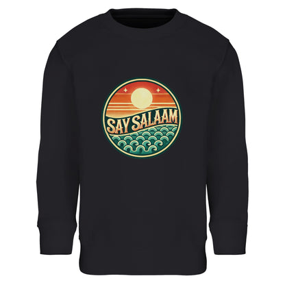 Say Salaam Sunset Glow Part-Recycled Cotton-Poly Kids Sweatshirt in Black, a deep black jet tone comparable to Zeus charcoal black. The circular sunset logo glows vibrantly against the dark background, highlighting warm orange sun gradients and teal ocean wave detailing. Constructed from cotton and recycled polyester with brushed fleece lining for warmth and durability. Ribbed cuffs and hem provide long-term shape retention. A sleek modest kids sweatshirt combining football culture and bold Muslim identity.