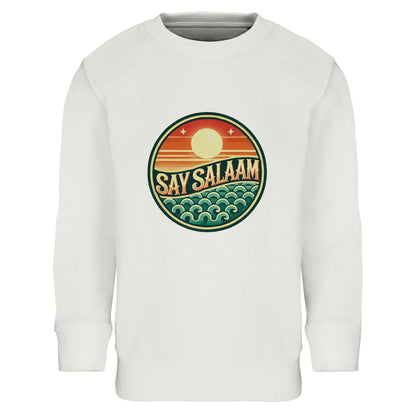 Say Salaam Sunset Glow Part-Recycled Cotton-Poly Kids Sweatshirt in White, a crisp white tone similar to platinum white with a clean bright finish. Circular Sunset Glow badge design across the chest, showing a rising sun over layered horizon lines and stylised ocean waves in warm sunset orange, deep red & teal green. Made from a cotton and recycled polyester blend with brushed fleece lining for warmth. Ribbed cuffs and hem provide durability for school, mosque visits and modest everyday streetwear.