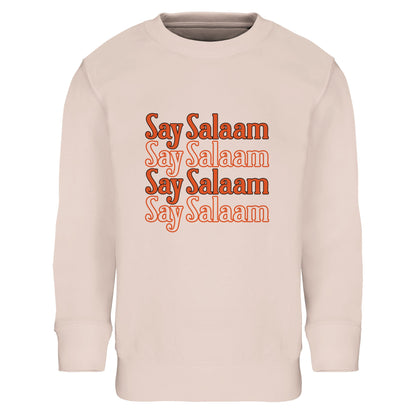 Say Salaam 4-Line Part-Recycled Cotton-Poly Kids Sweatshirt – Creamy Pink / Oyster Pink. Muslim kids sweatshirt with a centred four-line “Say Salaam” typographic print. The repeated text forms a compact block design with soft tonal layering in warm orange shades. The structured horizontal stacking creates visual rhythm while maintaining a gentle, friendly mood. Soft pink base contrasts beautifully with the bold lettering for a playful yet confident Islamic streetwear look in a cheap, high quality jumper.