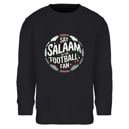 Say Salaam to the Football Fan Design #1 Part-Recycled Cotton-Poly Kids Sweatshirt – Black / Deep Black. Islamic youth football sweatshirt featuring a circular badge graphic with high-contrast white and green typography over a dark pitch-textured centre. The round crest silhouette is framed by subtle red detailing and glowing stadium beams, delivering a powerful, night-game atmosphere. Classic supporter badge styling for Muslim kids who love football culture and league fixtures.