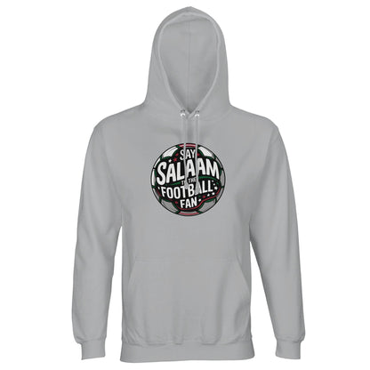 Ash / Silver Chalice unisex hoodie featuring the Say Salaam to the Football Fan Design #1 round emblem print. The circular football-inspired badge uses deep charcoal, black and forest green tones with subtle red and a floodlit stadium effect behind lettering. The balanced symmetry of the crest shape has a classic supporters’ badge aesthetic with a confident, heritage tone. Muslim football fan apparel for league matches, grassroots tournaments and Islamic youth gatherings, merging faith with footie culture.