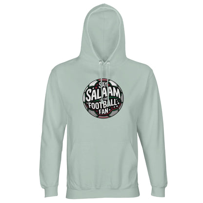 Creamy Green / Greenish Grey Islamic unisex hoodie featuring the Say Salaam to the Football Fan Design #1 round football badge graphic. The emblem’s circular silhouette contains layered typography over a dark pitch-inspired background with green, black and white contrasts and a subtle stadium glow. Its balanced crest shape and bold framing lines create a heritage club-style aesthetic with a modern Islamic message. Muslim football fan apparel for players, supporters and youth academies.