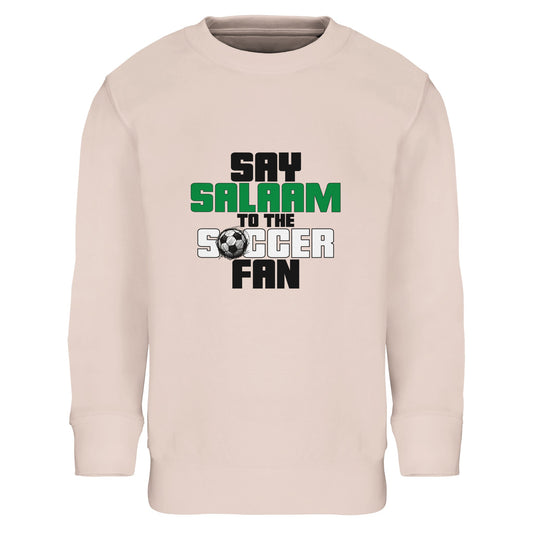 Say Salaam to the Soccer Fan Original Part-Recycled Cotton-Poly Kids Sweatshirt – Creamy Pink / Oyster Pink. Youth Islamic soccer sweatshirt showcasing a stacked text design with bold black and green lettering and a subtle football graphic detail. The vertical layout keeps the message clear and strong, with “Say Salaam” sitting above “Soccer Fan” in a structured, block-style font. Soft pastel tone meets confident sporty typography, blending Muslim identity with grassroots soccer pride for kids on matchdays.