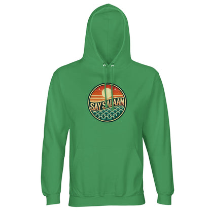 Spring Green / Sea Green unisex hoodie featuring the Say Salaam Sunset Glow circular skyline graphic in warm sunset tones of orange, red and teal. The round badge-style chest print frames a peaceful horizon scene with layered waves and bold SAY SALAAM lettering at centre. Vibrant green fabric amplifies the warmth of the sunset palette, creating balanced contrast and strong visual focus. Designed as modest Muslim streetwear, this brushed fleece hoodie blends Islamic identity, faith-based fashion and everyday